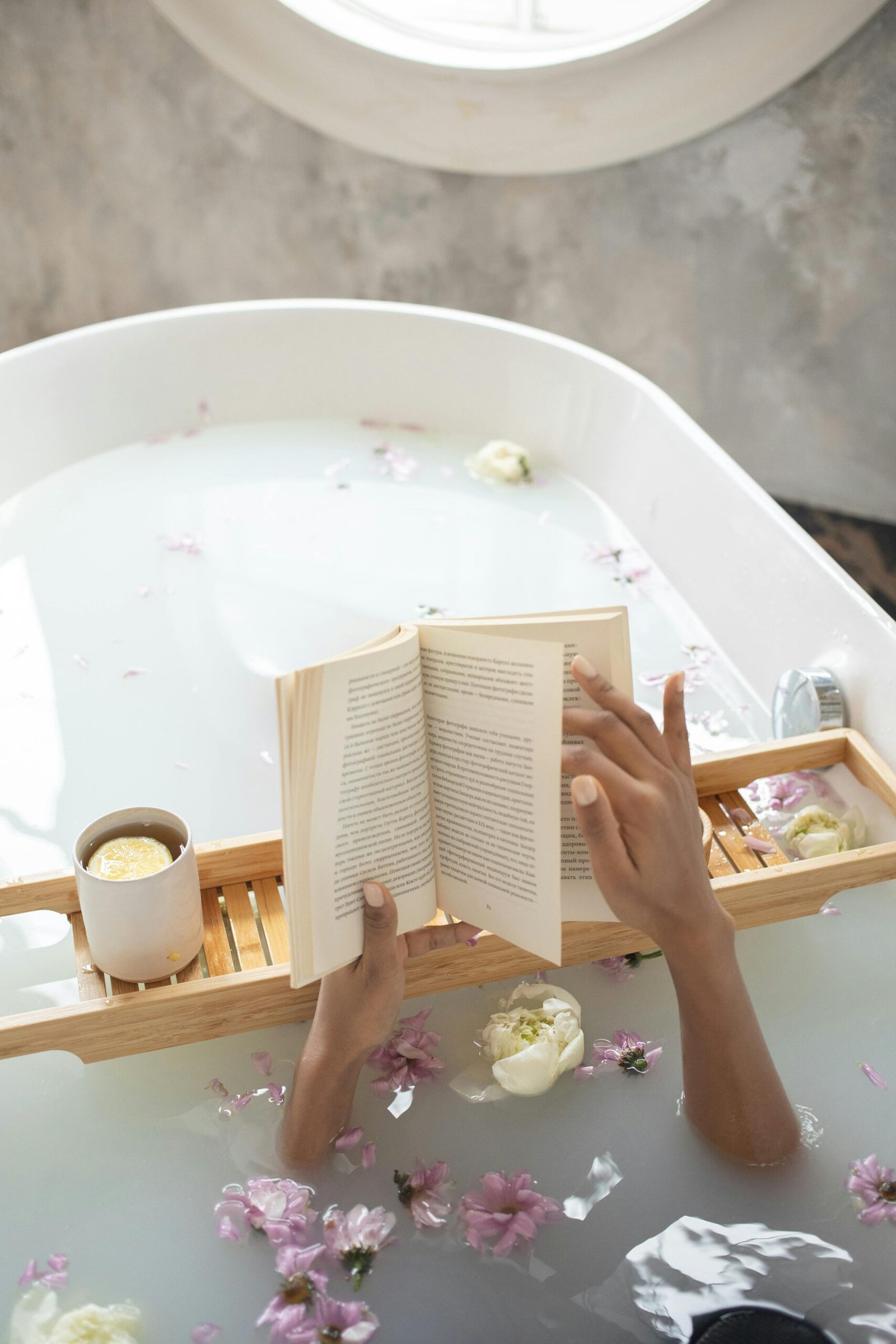 A tranquil scene of relaxation, reading a book in a flower-filled bathtub.