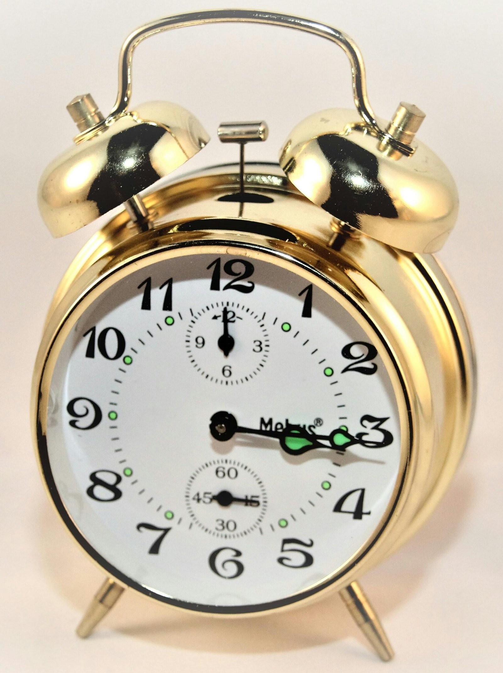 A classic brass alarm clock featuring twin bells and a white face with black numbers.